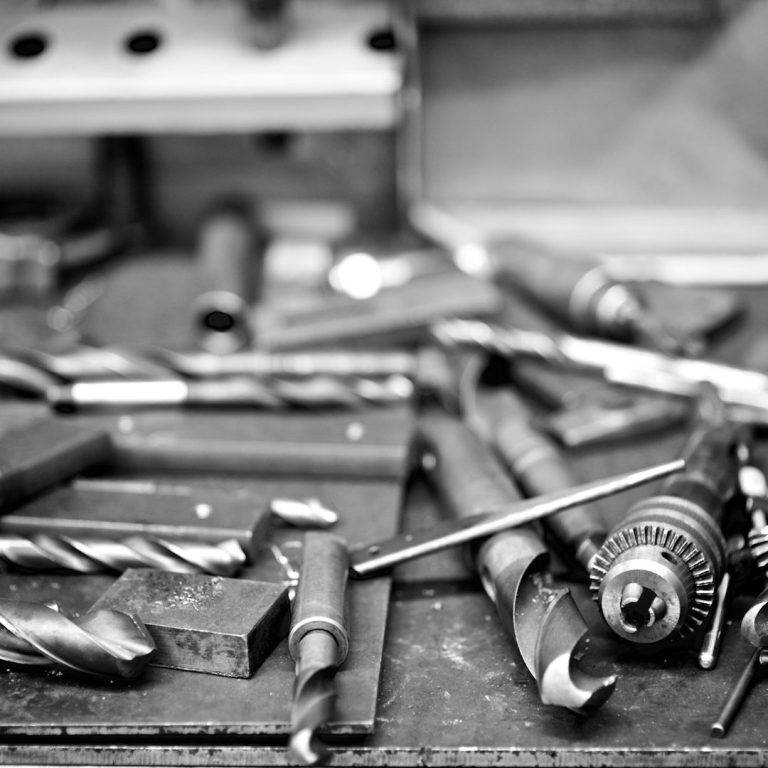 Assorted metal tools, including drill bits and a chuck, scattered on a workbench.